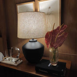 Buriti Table Lamp by Geo Contemporary in Graphite with a Rustic Linen shade beside red anthuriums