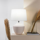 Buriti Table Lamp by Geo Contemporary in White with a White shade on a console beside dried grasses