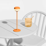Cheerio Table Lamp - Sunny Orange, on a bistro table