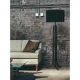 Forma Floor Lamp by Cerno with a black shade beside a sofa against a brick wall