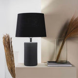 Jatobá Table Lamp by Geo Contemporary in Graphite with a Black shade on a console beside dried grasses