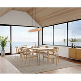 Lex Linear Pendant by Cerno in white washed oak over a dining table with an ocean view