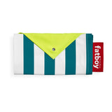 Folded teal-and-white striped beach blanket with neon-yellow corner flap, snap closure, and red Fatboy strap — Miasun by Fatboy