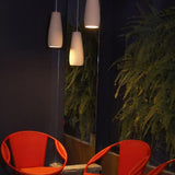 Phobos Ceramic Pendant Light by Geo Contemporary in White, a cluster of pendants glowing beside orange wicker chairs
