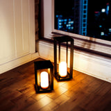 Siroco Portable Lantern - Small and Large, lit on a wooden floor