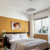 Sunset Ceramic Pendant Light by Geo Contemporary in White hanging in a bedroom with an ochre accent wall
