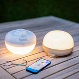Cherry Portable Light - Beige and White, lit on an outdoor table