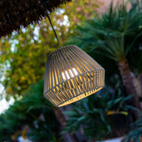 Conta Portable Pendant Light - Taupe, lit under a thatched canopy