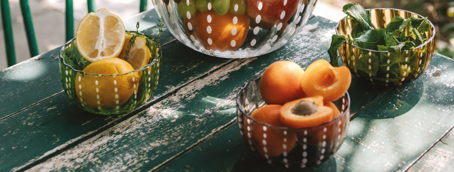 Glass serving bowls of fruit and herbs on a garden table | Casa Di Luce