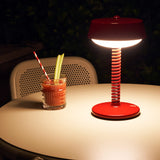 Bellboy Table Lamp - Lobby Red, lit on a cafe table