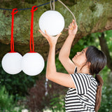 Bolleke Hanging Lamp - Red, hung from a tree branch