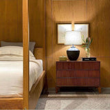 Buriti Table Lamp by Geo Contemporary in Graphite on a walnut nightstand in a warm wood-panelled bedroom
