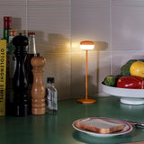 Cheerio Table Lamp - Sunny Orange, lit on a kitchen counter
