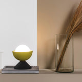 Don Ceramic Table Lamp by Geo Contemporary in Yellow and Graphite, lit, on a stack of books