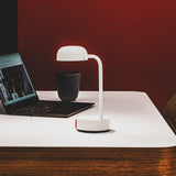 Fokus Battery Table Lamp - Cloudy White, beside a laptop