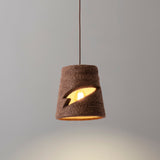 Myst Ceramic Pendant Light by Geo Contemporary in Cinnamon, lit against a grey studio wall