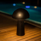 Shitake Portable Table Lamp - Black, on a poolside deck