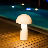 Shitake Portable Table Lamp - White, lit on a poolside deck