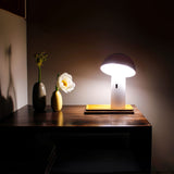 Shitake Portable Table Lamp - White, lit on a sideboard