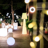 Lola Floor Lamp - 3000K, on a terrace behind string lights