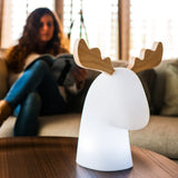 Rudy Reindeer Table Lamp - Solar and Rechargeable, beside a reader on a sofa