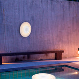Wally Play Disk Floating Speaker Light - hung on a wall by a pool